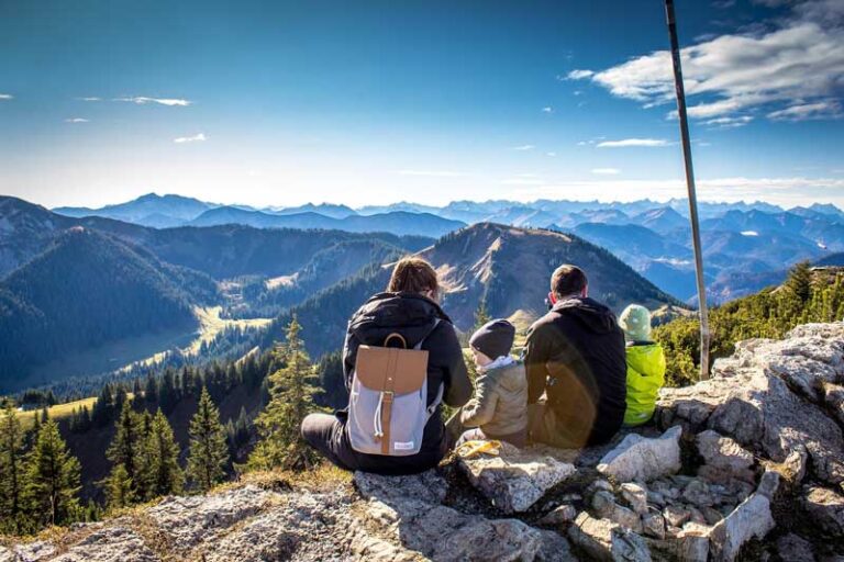 Nell'immagine una famiglia composta da mamma, papà e due bambini. Sono seduti mentre ammirano il panorama e trascorrono del tempo insieme.